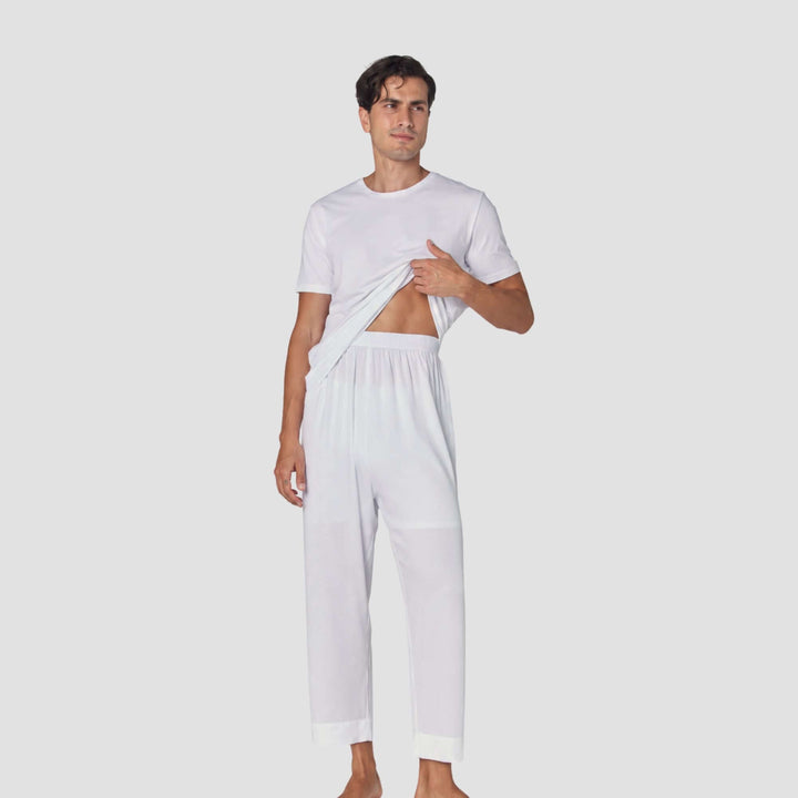 A man modeling a white two-piece loungewear set consisting of a short-sleeve crewneck t-shirt and matching relaxed-fit pants, shown against a solid light gray background.